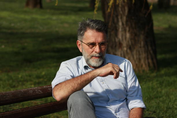 istock Senior man with glasses enjoy on bench in public park 1487357776