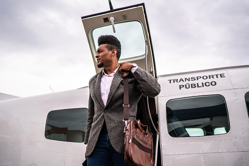 Mid adult businessman looking around when leaving a private jet