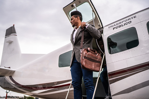 Mid adult businessman looking around when leaving a private jet