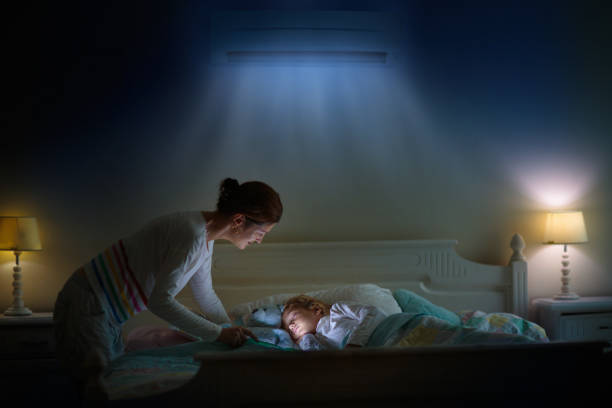 Air conditioner in bedroom. Kids room climate Air conditioner in bedroom. Kids room climate control. Mother and child in bed under cool air breeze. Comfortable temperature for healthy sleep on summer night. Air conditioning device in family home. air conditioner family stock pictures, royalty-free photos & images