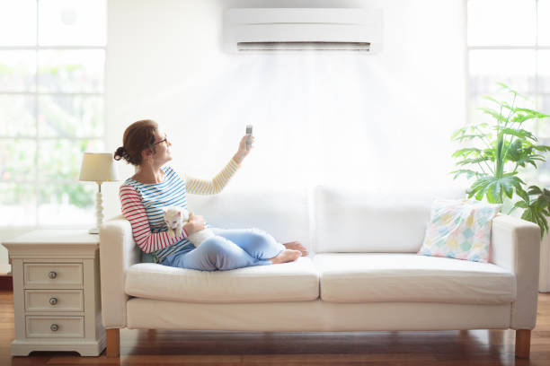 istock Woman with air conditioner remote control. 1487359098