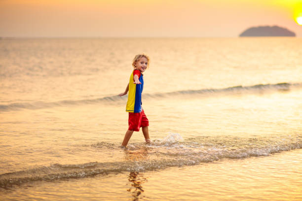 istock Child playing on ocean beach. Kid at sunset sea. 1487359241