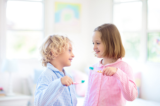 Child brushing teeth. Kids with toothpaste and brush. Dental and oral hygiene, care. Healthy daily routine for children. Kid after shower or bath at home. Girl and boy in pajamas with tooth paste.