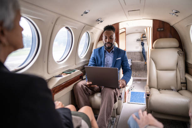 homme d’affaires adulte travaillant avec un ordinateur portable dans un avion privé - airplane travel commercial airplane isolated photos et images de collection