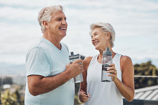 Senior couple, fitness and water bottle with smile for hydration or thirst after workout, exercise or training in nature. Happy elderly man and woman smiling for natural refreshment from exercising