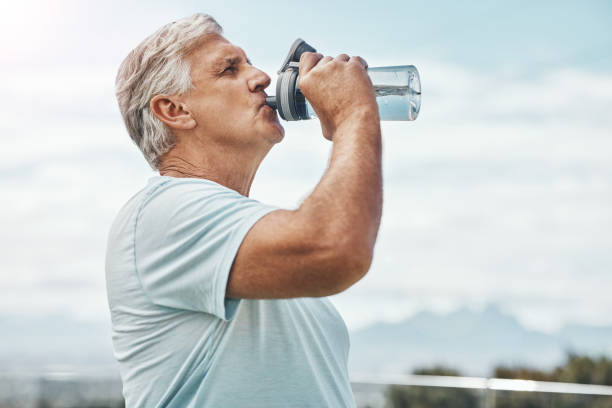 istock Senior man, fitness and drinking water for hydration or thirst after workout, exercise or training in nature. Elderly male having refreshing natural liquid drink from intense cardio in the outdoors 1487361097