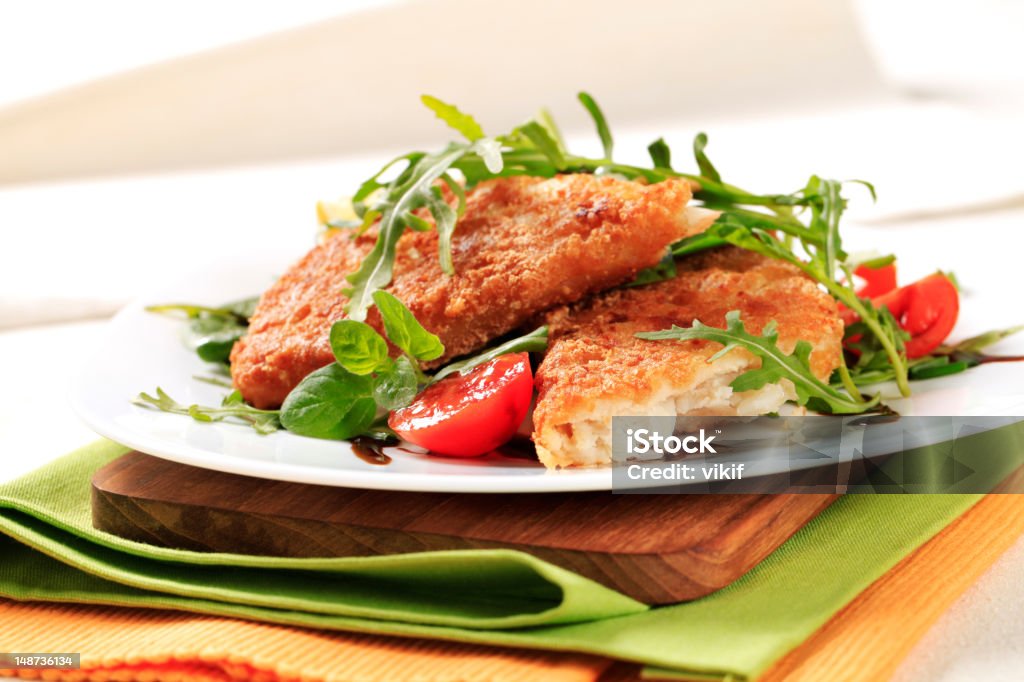 Fried fish and fresh salad Fried fish on a bed of fresh salad Arugula Stock Photo