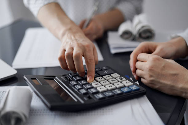 istock Woman accountant using a calculator and laptop computer while counting taxes for a client. Business audit and finance concepts 1487361427