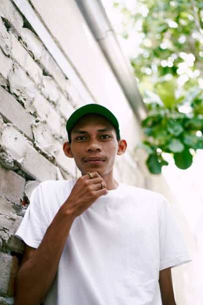 Asian man with hat looking at camera. Authentic portraiture.