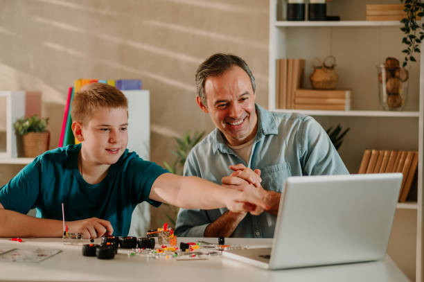 istock Father is looking with joy while his son is pointing his finger to the screen. 1487365368