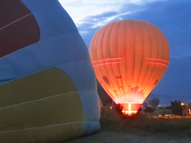 夜明け早朝の山のカッパドキアで多くの色とりどりの美しい風船を空中に打ち上げるプロセス。バーナーからの熱風でバルーンを満たし、バスケットを準備します。エクスカーション、上記� - turkey hot air balloon cappadocia basket ストックフォトと画像