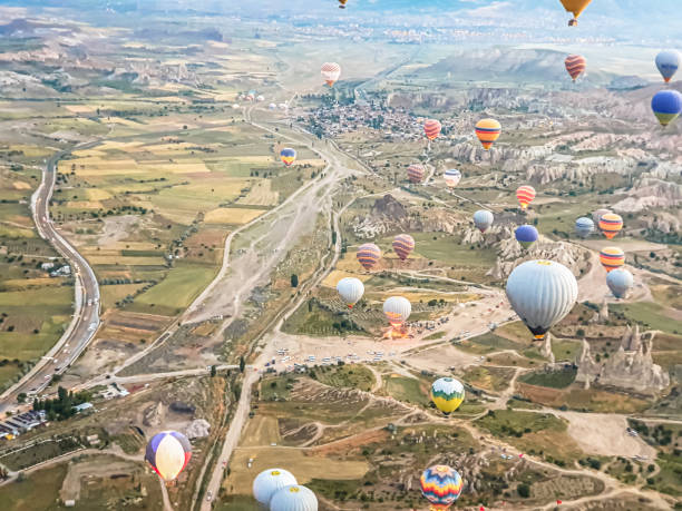 processo di lancio di molti bellissimi palloncini colorati in aria in cappadocia in montagna all'alba presto. riempimento del palloncino con aria calda dal bruciatore, preparazione del cestello. escursione, volo per i turisti sopra - cappadocia hot air balloon turkey basket foto e immagini stock