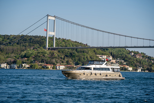 Luxury yacht in the Bosphorus. Bosphorus Bridge in the background. Istanbul, Turkey - May 2, 2023.