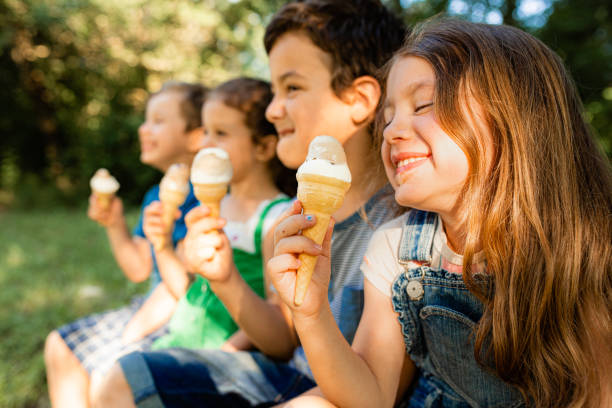 Children eating ice cream in the summer Group of children having fun licking ice cream cone in the yard licking ice cream cone stock pictures, royalty-free photos & images