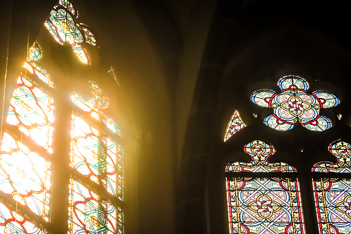 Sunlight seen through an old church window, given an aged effect. Cobwebs adorn the sides of the window, which is in a very rural church in Suffolk, Eastern England.