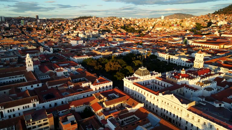 Aerial shot drone orbits to right around church on main square with sun behind drone at sunset