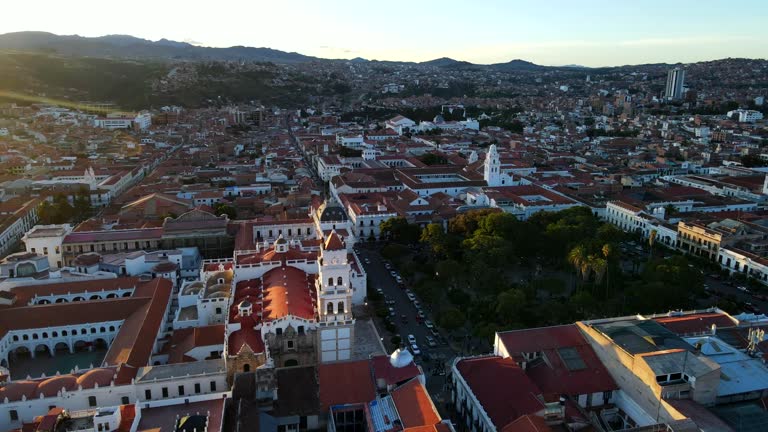 Aerial shot drone orbits to right around buildings with sun behind