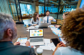 Diverse group of people meeting and working at a board room table at a business presentation or seminar.