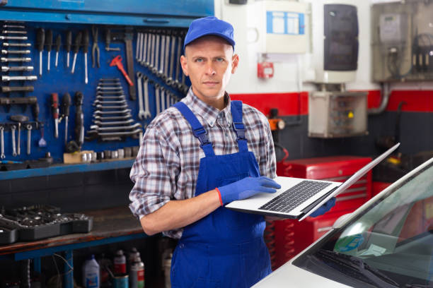 istock Mechanic man with laptop making car diagnostics at service 1487380601
