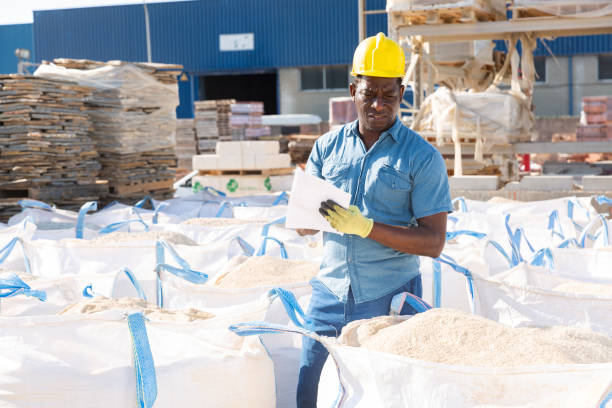 Man standing amongst bags in construction material storage