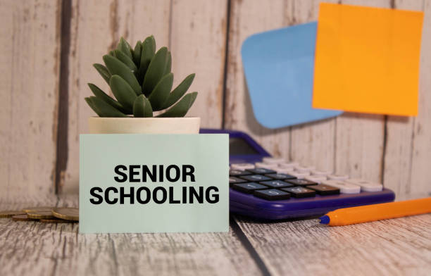 istock White card with the text Senior Schooling on study desk. 1487380682