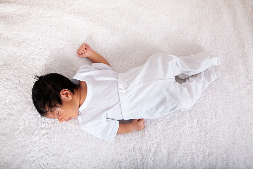 African American newborn baby sleeping on a white mattress