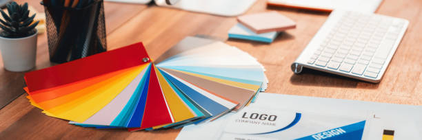 istock Graphic designer's workspace features color palette and laptop. Scrutinize 1487387417