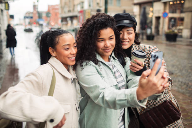 istock Three young women using a phone on a city street 1487389105