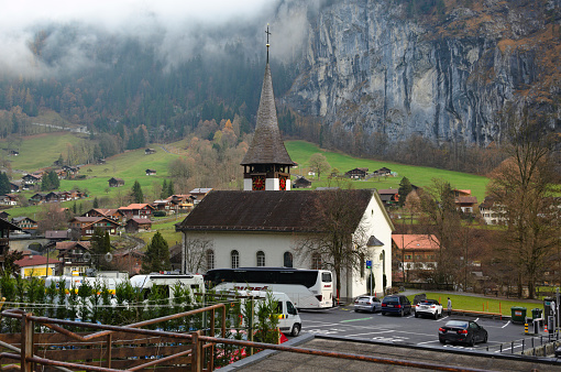 Lauterbrunnen, Switzerland - December 1, 2022: Vehicles of tourists and locals parked in front of the church