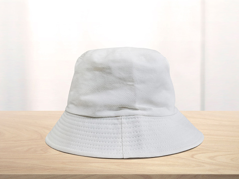 white bucket hat on wooden table There is a white mirror in the background.