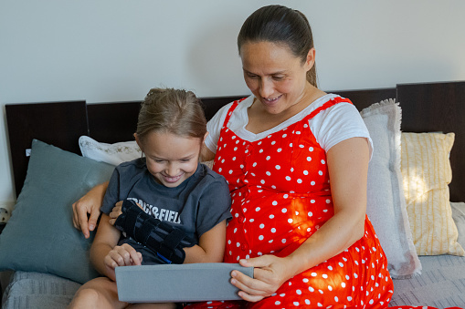 Girl watches movie on tablet with mom. Childcare and parental control on use of mobile devices.