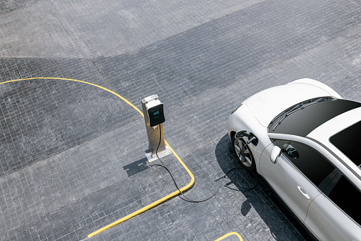 Aerial top view image of progressive green energy-powered charging station, electric vehicle at public car park with EV car concept for alternative transportation and energy infrastructure.