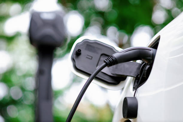 istock Focus EV charger device into progressive EV car with blur charging point. 1487397117