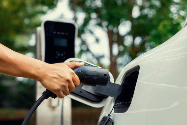 istock Focus hand insert progressive EV charger plug to EV car with blur background. 1487397149