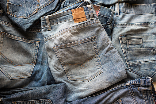 Top view of folded jeans,Blue jeans on a stack of jeans . Top view of various denim fabrics on white background. Several long jeans