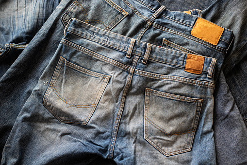 Top view of folded jeans,Blue jeans on a stack of jeans . Top view of various denim fabrics on white background. Several long jeans