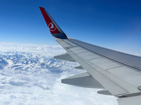 Budva, Montenegro - April 11, 2023: View to the Turkish Airlines aircraft wing from the window. Flight over the snowy mountains range