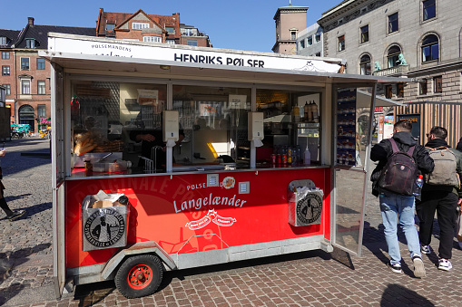 Copenhagen, Denmark April 9, 2023 A small red wagon sells hot dogs and Danish sausages on a square in old town.