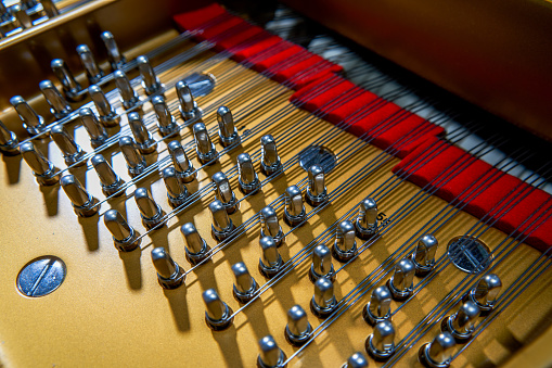 A close-up of the internal string structure of a top grand piano