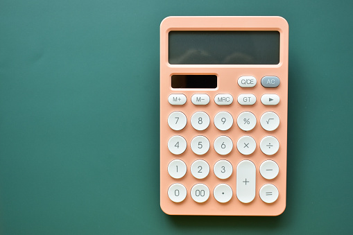 modern peach colour pastel calculator and white button on green background, business and finance accounting concept