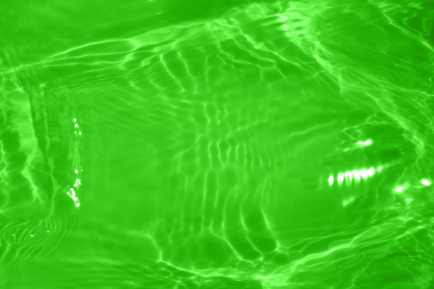 Light green water with ripples on the surface. Defocus blurred transparent colored clear calm water surface texture with splashes and bubbles. Water waves with shining pattern texture background.