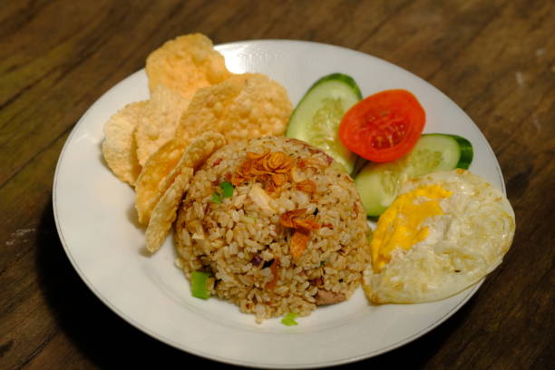 istock Nasi Goreng Telur Mata Sapi. fried rice is white rice fried with garlic, shallot, chilies, salt, and shrimp paste. Served with fried eggs, tomato and cucumber slices, and crackers. Indonesian food. 1487410957