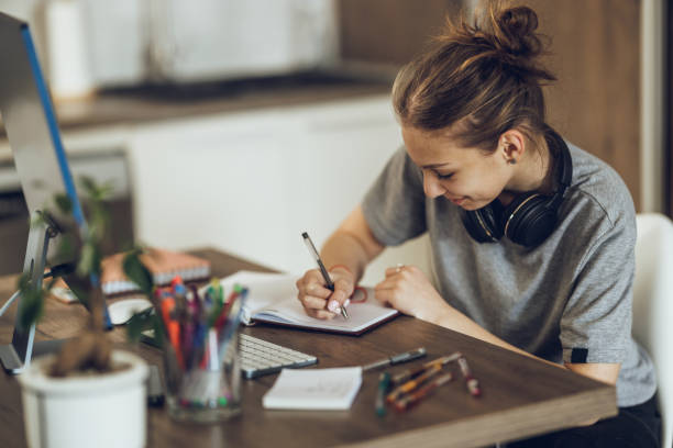 istock Teen Girl Writing In Her Notebook While Learning At Home 1487412845
