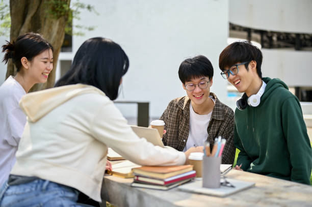 istock Group of cheerful Asian college students enjoy talking while tutoring math at a campus park 1487413963