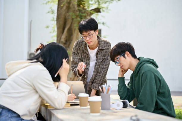 istock Smart Asian male college student explained and helped his friends with math homework 1487413970