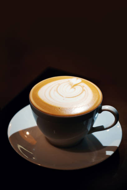 istock Cup of coffee latte with heart shape on black background 1487416327