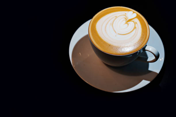 istock Cup of coffee latte with heart shape on black background 1487416328