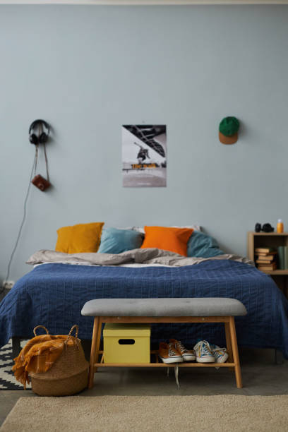 istock Double bed with group of multi-color cushions standing against grey wall 1487419568