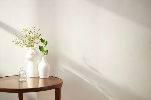 Vases and objects on the table in a warm room with sunlight\ncoming in