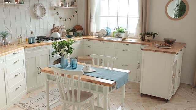 Modern light Scandinavian kitchen with a wooden worktop filled with kitchen accessories. Stylish kitchen with large window, potted plants and wooden dining table with a bouquet of flowers. Nobody